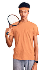 Young african american man playing tennis holding racket thinking attitude and sober expression looking self confident