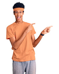 Young african american man wearing sportswear smiling and looking at the camera pointing with two hands and fingers to the side.