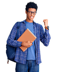 Young african american man wearing student backpack holding book very happy and excited doing...