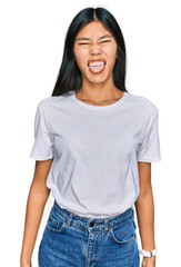 Obraz premium Beautiful young asian woman wearing casual white t shirt sticking tongue out happy with funny expression. emotion concept.