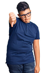 Little boy kid wearing casual clothes and glasses looking unhappy and angry showing rejection and negative with thumbs down gesture. bad expression.