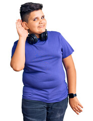 Little boy kid listening to music wearing headphones smiling with hand over ear listening an hearing to rumor or gossip. deafness concept.