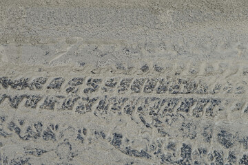 Empreintes de pneus dans du sable mouillé sur une route