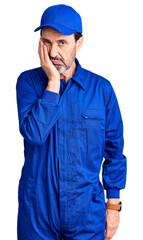 Middle age handsome man wearing mechanic uniform thinking looking tired and bored with depression problems with crossed arms.