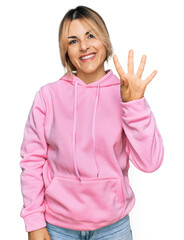Obraz na płótnie Canvas Young caucasian woman wearing casual sweatshirt showing and pointing up with fingers number four while smiling confident and happy.