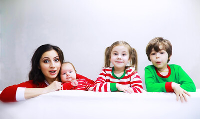 A family in striped pajamas is resting at home. Little children dressed as elves are lying on the sofa. Happy familywith banner.