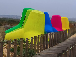 Colorful concrete breakwaters on the beach with a wooden foot path
