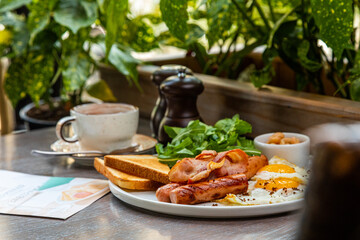 Breakfast with fried eggs, bacon, beans and fresh vegetables