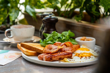 Breakfast with fried eggs, bacon, beans and fresh vegetables