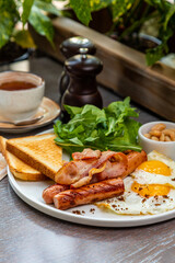 Breakfast with fried eggs, bacon, beans and fresh vegetables