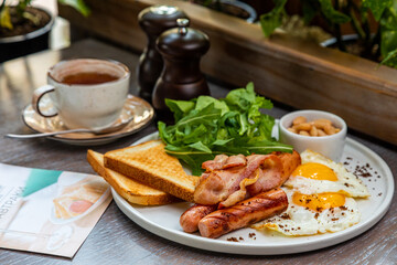 Breakfast with fried eggs, bacon, beans and fresh vegetables
