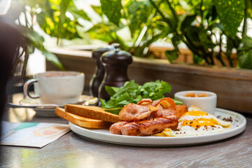 Breakfast with fried eggs, bacon, beans and fresh vegetables