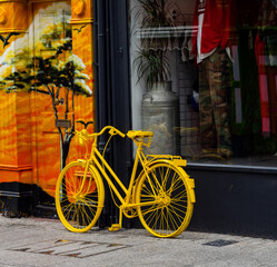 Fototapeta na wymiar Yellow painted old bicycle beside the shop window, Michael Street,Waterford, Ireland