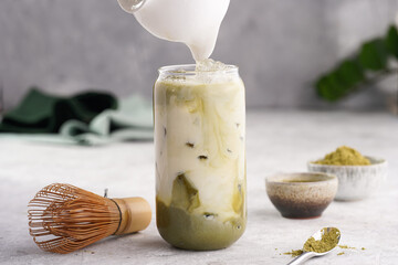 Pouring milk into tall boba tea glass with ice, matcha green tea to make matcha latte