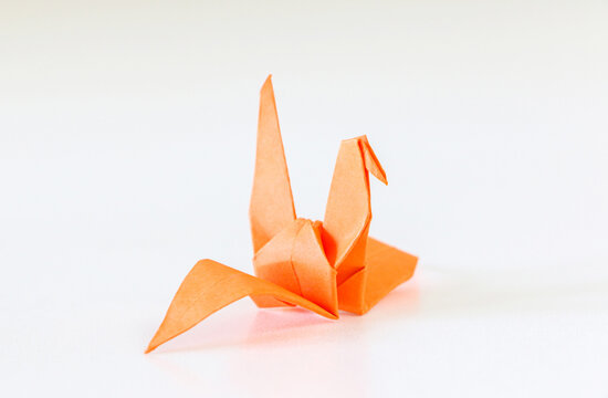 Handcrafted orange Japanese origami crane on white background