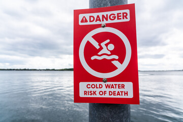 red Warning sign located at waterfront to inform people,  