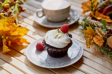 Aesthetic french gluten and sugar free cupcake close up among autumn atmospheric decoration and cup of coffee. Cozy breakfast