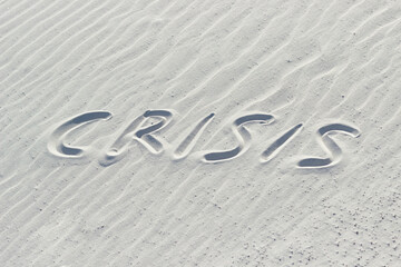 crisis written with finger on white sand, crisisas concept, word on sand