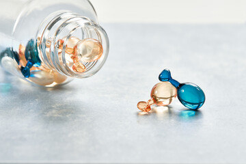Close-up on mint blue and orange serum capsules for healthy skin in transparent bottle....