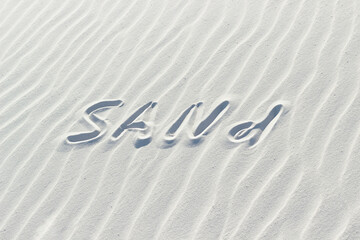 sand written with finger on white sand, word on sand