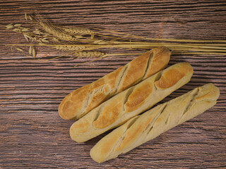 Homemade french style loaves of bread on wooden background and with wheat and oatmeal decoration