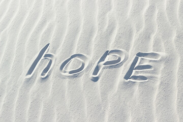 hope written with a finger on the white sand. concept, word on sand