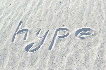 hype written with a finger on the white sand. popularity and trend concept, word on sand