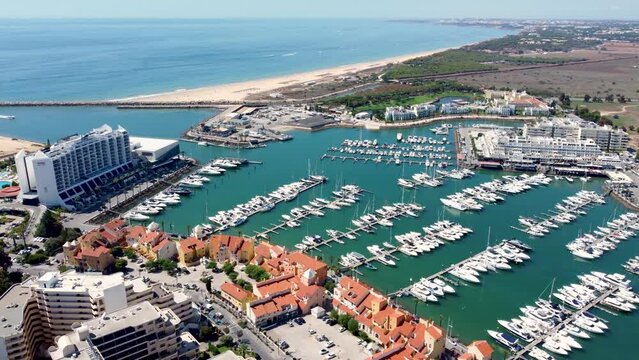 Vilamoura, PORTUGAL: September 18 2022:. Beautiful aerial perspective of Vilamoura marina. Luxury hotels, yachts docked in the port. Famous travel destination in south of Portugal. Drone backward