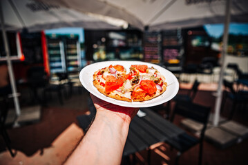 man holds paper plate with mini pita pizza in hands. Street food, fast food outdoor