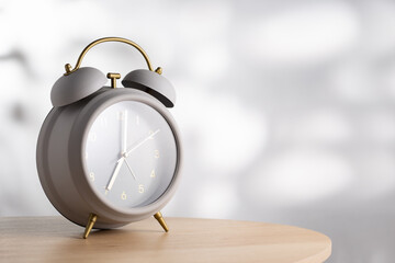 Minimalist gray alarm clock on the wooden table and morning light