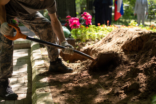 Man digs grave. Guy with shovel digs ground. Funeral details.