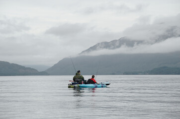 Fishing from kayak on calm water surrounded by mountain scenery Scotland