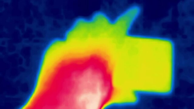 The hand shoots a night video on a smartphone. The concept of the smartphone generation that does not part with the gadget even at night. Image from thermal imager device.