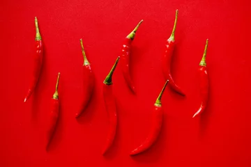 Fotobehang rode hete chilipepers op rode achtergrond © amonphan