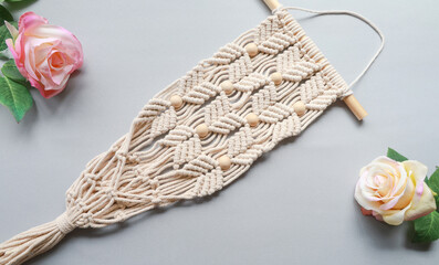 macrame plant holder and flower on grey background