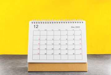 december calendar 2022 on the wooden table on a yellow background.