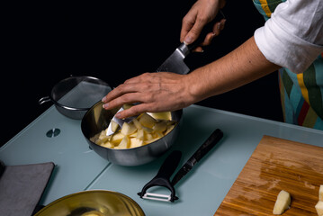 Working in the kitchen. Depositing apple pieces in a steel bowl.