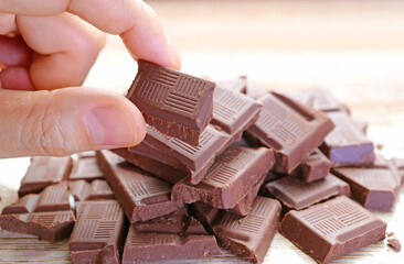 Closeup Man's Fingers Picking a Chunk of Chocolate from Its Pile
