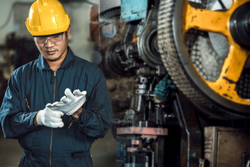 Asian engineer mechanic man checking and using wrench for maintenance pressing metal machine at...