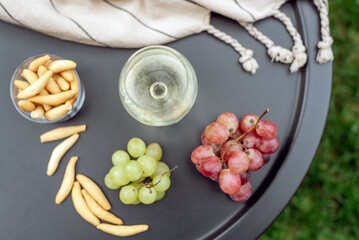 A glass of white wine with appetizers on the garden table.
