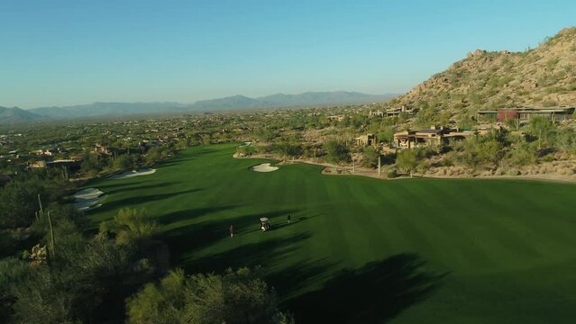 Aerial of beautiful golf course in Scottsdale, Arizona against desert hills at sunset