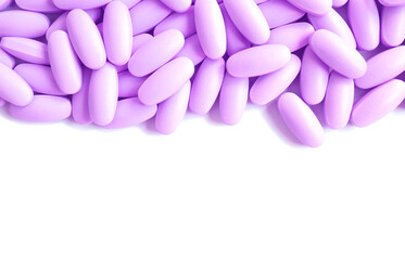 Heap of lavender purple pills on white background with copy space