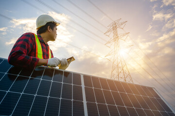 A male electrical engineer looks at a power station and solar photovoltaic panels to see the power generation planning work at a high voltage pole.