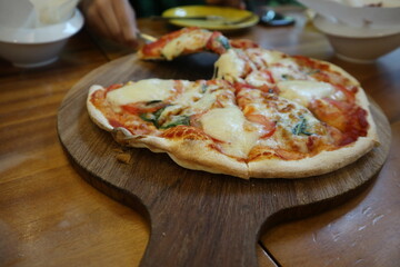 child eating delicious Pizza Margherita on the wooden plate close-up