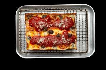Detroit pizza with meat and sauce on an iron tray