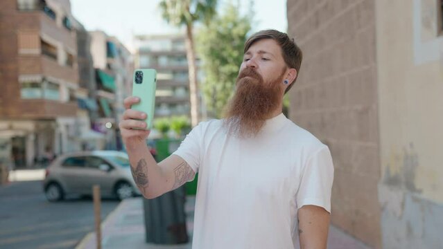 Young redhead man smiling confident making selfie by the smartphone at street