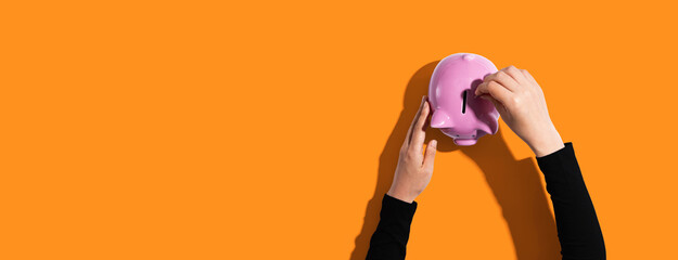 Person depositing money in a pink piggy bank