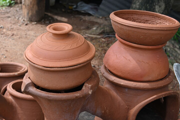 A cooking clay pot with covering lid on top with a another large cooking clay pot on a double clay...