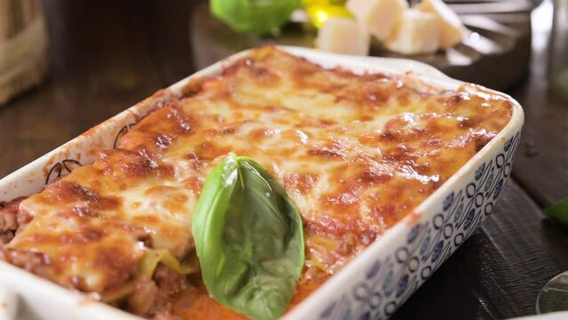 Lasagna with pesto.Italian lunch,homemade green lasagna with spinach in the dough, ragu - meat sauce, bechamel and parmesan cheese. illage dining atmosphere in Italy. Glass of wine is poured. 4k 