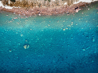 Turquoise water by the rocky shore in Sardinia seen from above